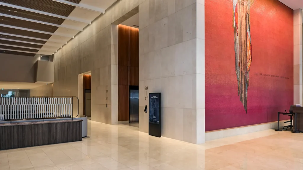 Freestanding Digital Tenant Directories in very large commercial building Foyer. A big textured brighly coloured mural can been seen at the front of the main lift well.