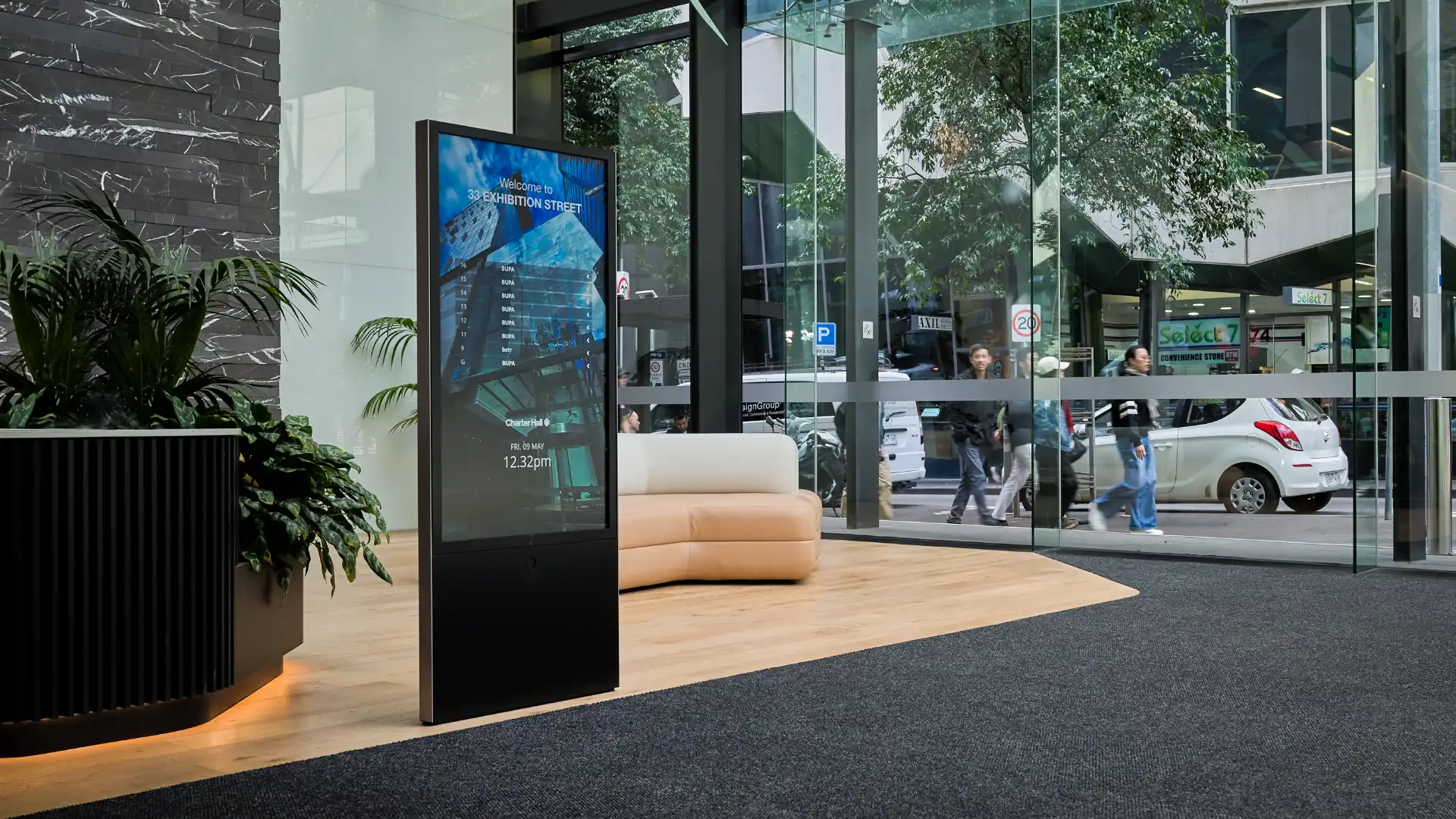 Freestanding Digital Tenant Directory in the large light filled foyer of 33 Exhibition Street Melbourne. People can be seen walking past in the street outside