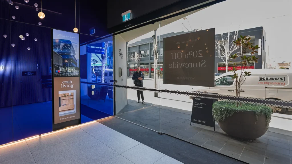 Multi-Screen Digital Tenant Directory in the foyer of 600 Church St Cremorne. People entering foyer showing street scene outside.